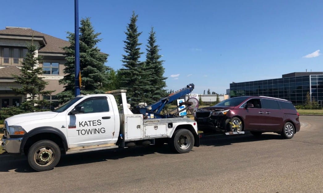 A purple car tow by white car Kates Towing Company